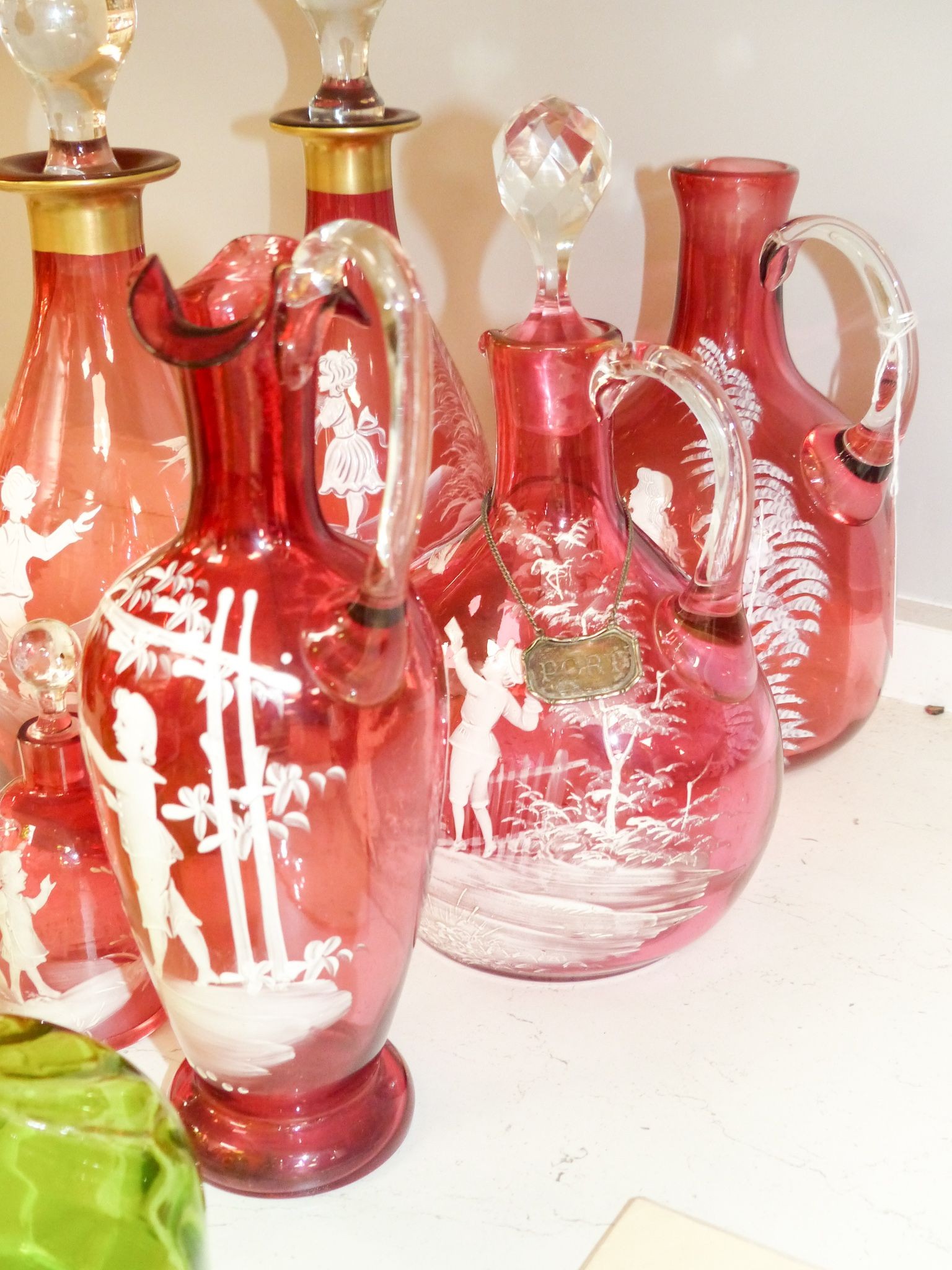 A collection of Mary Gregory cranberry and green glass decanters, jug etc (9), tallest 28.5 cm